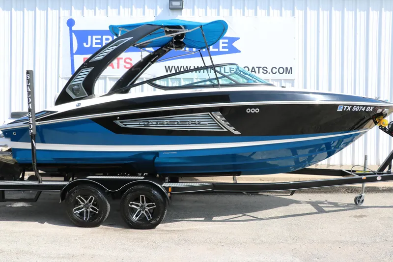 Slide: The Image of 2018 Regal 23 RX Surf boat in blue and black on a trailer, side view. - 16