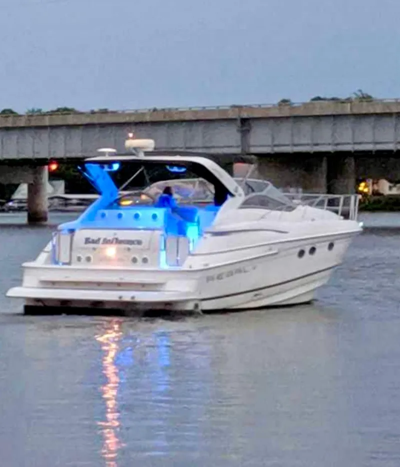 Slide: The Image of 2001 Regal Commodore 4160 yacht with blue lights on a calm river near a bridge. - 3