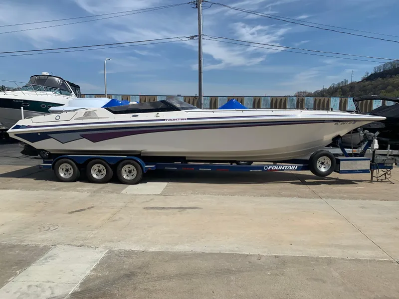 Slide: The Image of 1996 Fountain 32 Fever speedboat on trailer, parked outdoors under clear sky. - 0