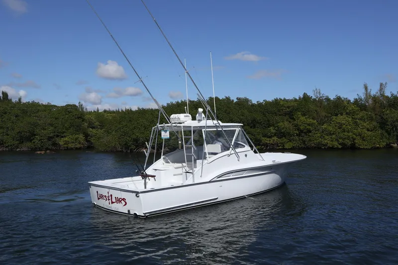 Slide: The Image of 2002 Miller Marine 36 Express boat on calm water, surrounded by lush greenery. - 34
