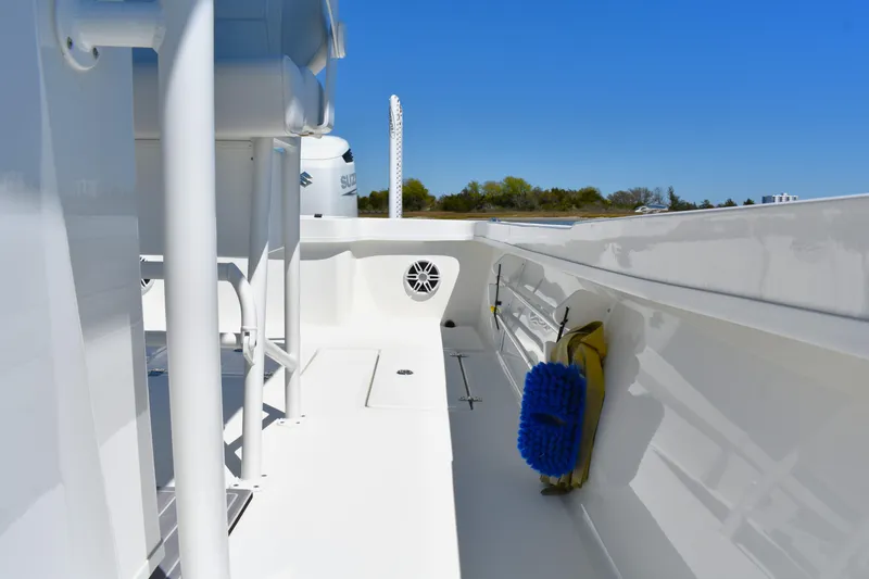 Slide: The Image of 2023 Pair Customs 24 Center Console MV boat deck with cleaning brush, under clear blue sky. - 29