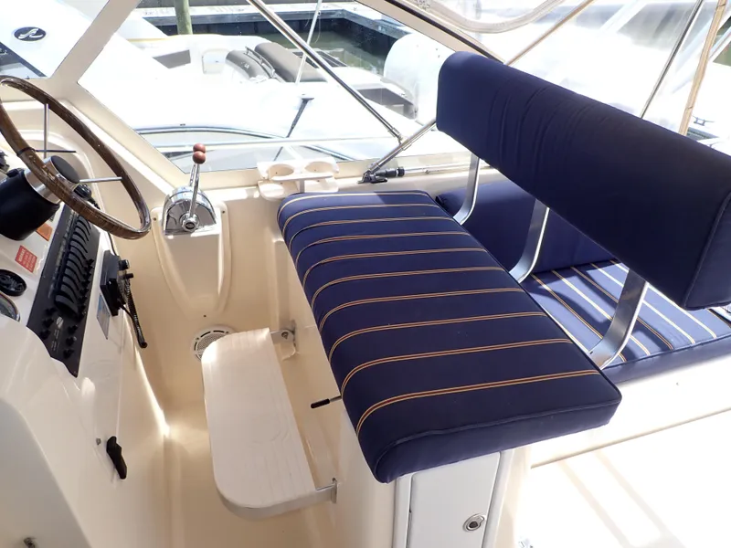 Slide: The Image of 2004 Mainship 34 Rum Runner II helm with blue striped seating and steering wheel. - 12