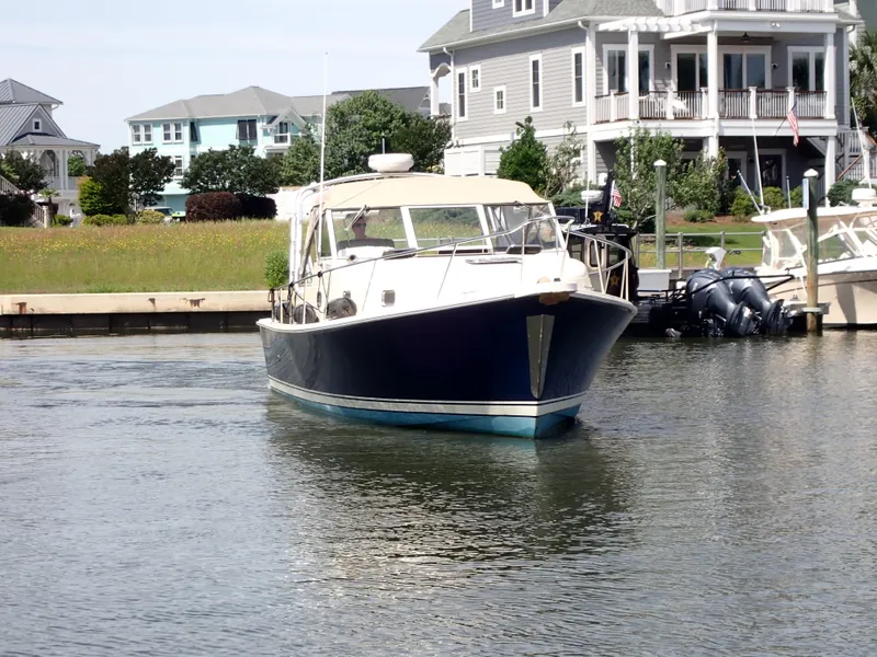Slide: The Image of 2004 Mainship 34 Rum Runner II boat docked near waterfront homes. - 2