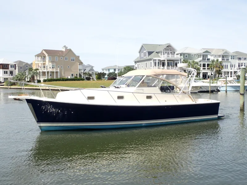 Slide: The Image of 2004 Mainship 34 Rum Runner II yacht docked near waterfront homes. - 3