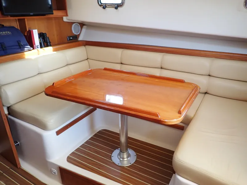 Slide: The Image of 2004 Mainship 34 Rum Runner II interior with beige seating and wooden table. - 30