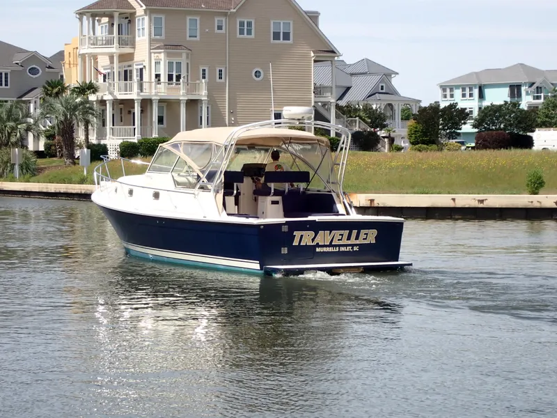 Slide: The Image of 2004 Mainship 34 Rum Runner II cruising near waterfront homes. - 4