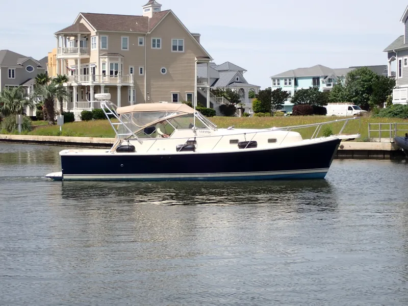 Slide: The Image of 2004 Mainship 34 Rum Runner II yacht docked near waterfront homes. - 5
