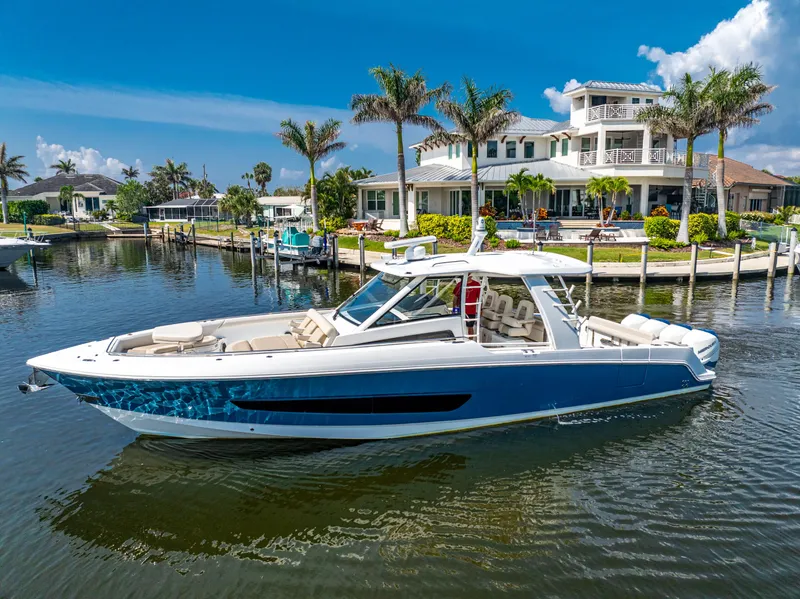 Slide: The Image of 2019 Boston Whaler 420 Outrage docked, featuring spacious seating and canopy, in a sunny marina. - 23
