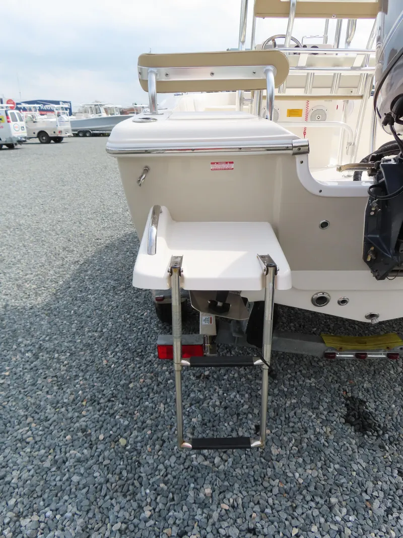 Slide: The Image of 2019 Key West 176 Center Console boat with rear swim ladder on gravel surface. - 6