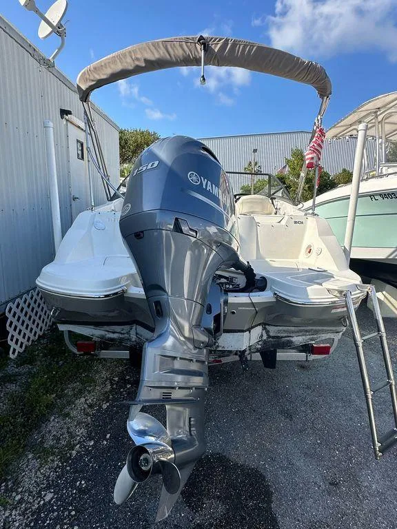 Slide: The Image of 2022 Stingray 201 DC boat with Yamaha outboard motor, docked outdoors. - 2