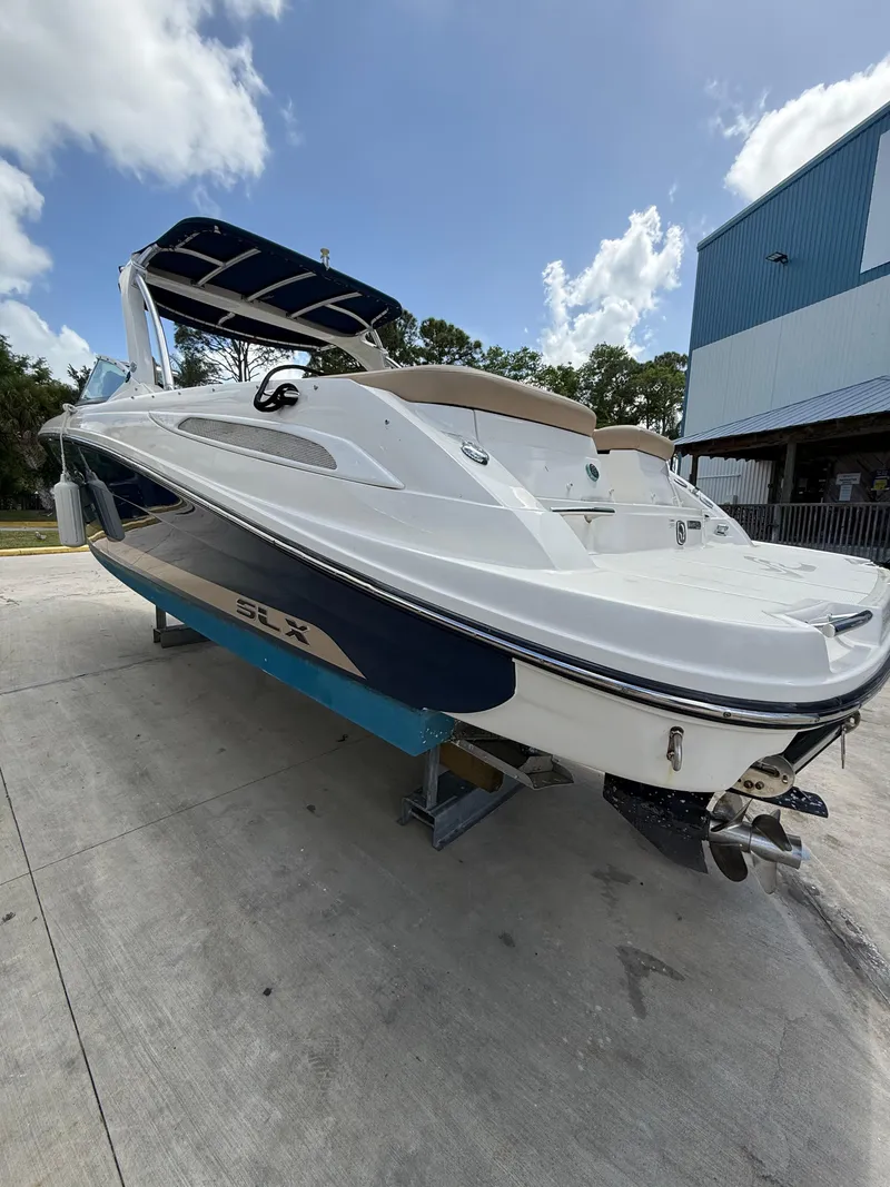 Slide: The Image of 2014 Sea Ray 270 SLX boat on trailer, white and blue, parked outdoors. - 2