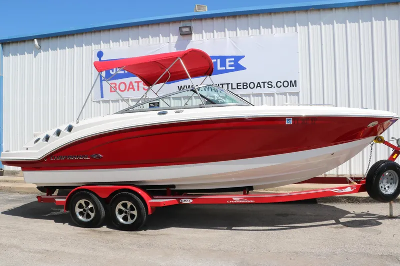 Slide: The Image of 2016 Chaparral 246 SSi boat with red hull and trailer, parked outside a building. - 1