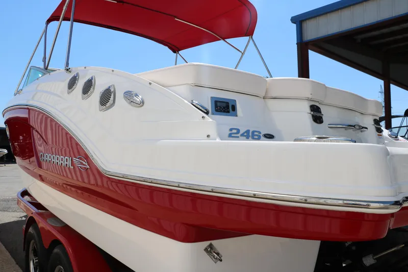 Slide: The Image of 2016 Chaparral 246 SSi boat with red and white exterior, docked under a canopy. - 7
