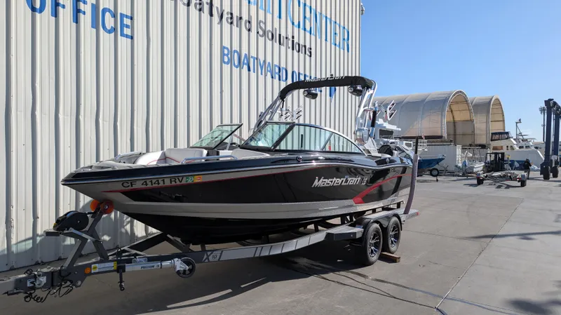 Slide: The Image of 2015 MasterCraft X10 boat on trailer, parked outside a boatyard facility. - 1