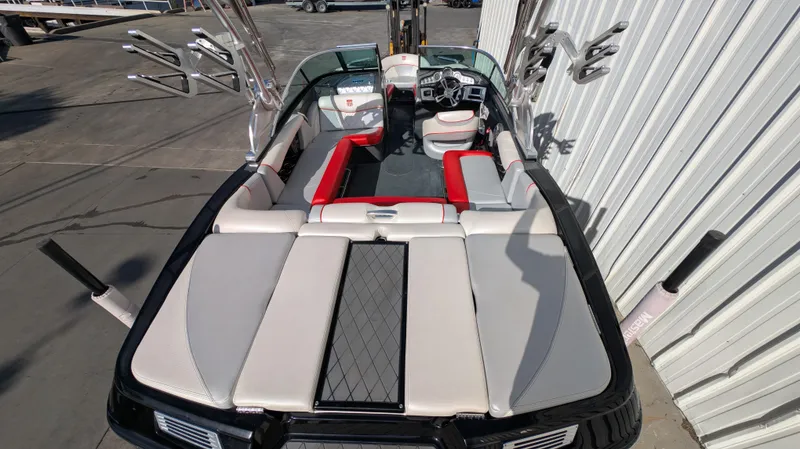 Slide: The Image of 2015 MasterCraft X10 boat interior with red and gray seating, docked near a building. - 16