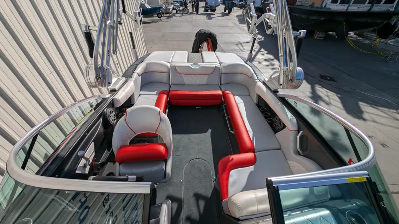 Slide: The Image of 2015 MasterCraft X10 boat interior with red and white seating, docked outdoors. - 17