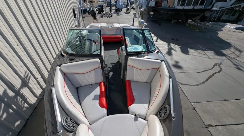 Slide: The Image of 2015 MasterCraft X10 boat interior with red and white seating, docked outdoors. - 19