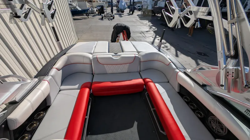 Slide: The Image of 2015 MasterCraft X10 boat interior with red and white seating, docked outdoors. - 20