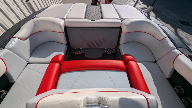 Slide: The Image of 2015 MasterCraft X10 boat interior with white and red seating, cup holders, and sleek design. - 22
