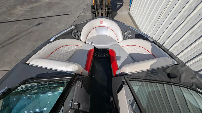 Slide: The Image of 2015 MasterCraft X10 boat interior with gray and red seating, docked near a metal building. - 24