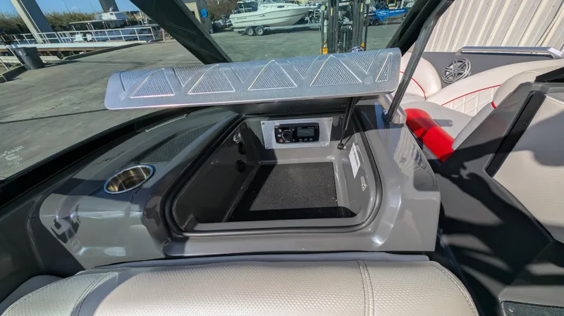 Slide: The Image of 2015 MasterCraft X10 boat interior with open storage compartment and cup holder. - 30