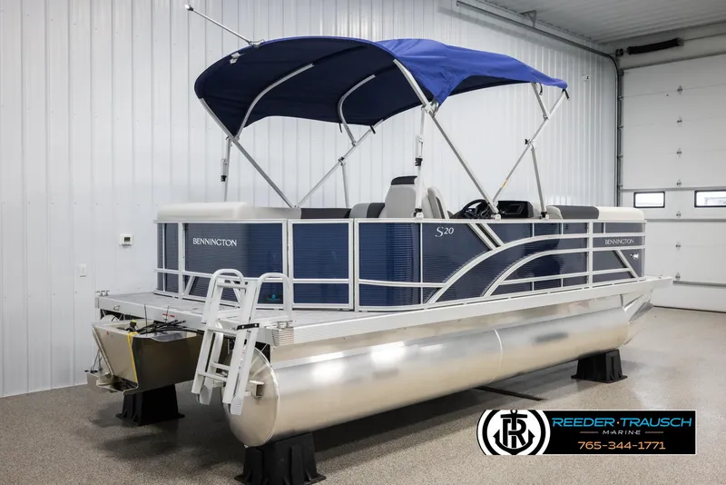 Slide: The Image of 2025 Bennington 20 SLSE pontoon boat with blue canopy in a showroom. - 6