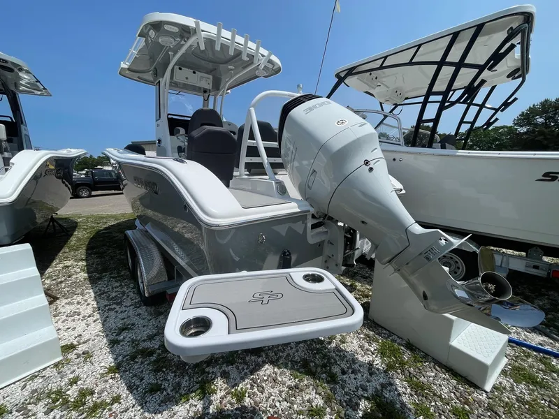Slide: The Image of 2025 Sea Pro 245 Sandbar boat with outboard motor, displayed outdoors. - 2