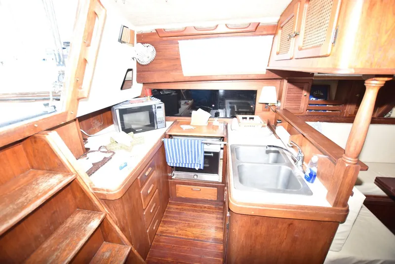Slide: The Image of 1983 S2 Sloop interior with wooden cabinetry, kitchen sink, and microwave. - 11