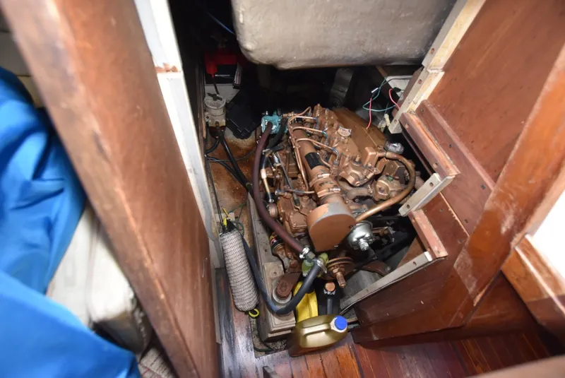 Slide: The Image of Engine compartment of a 1983 S2 Sloop sailboat, showing mechanical components and wooden interior. - 12