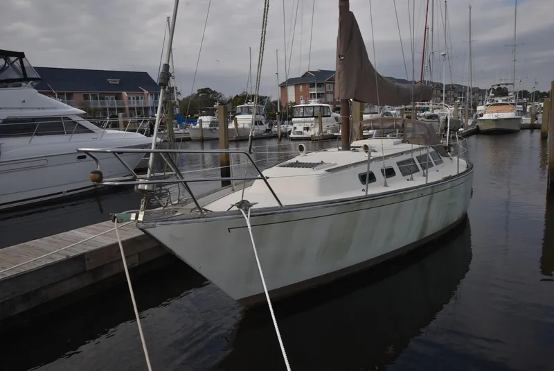 Slide: The Image of 1983 S2 Sloop sailboat docked in a marina, surrounded by other boats. - 14