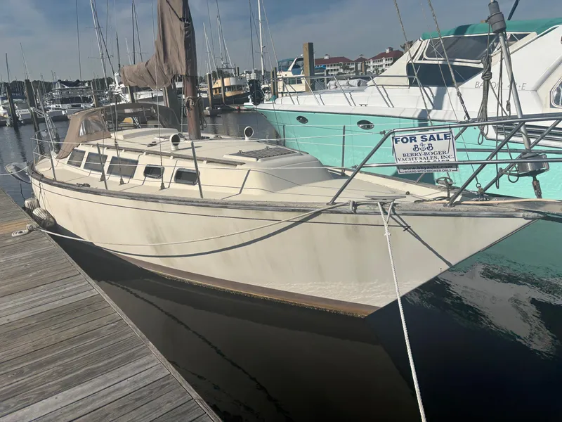 Slide: The Image of 1983 S2 Sloop sailboat docked, for sale sign visible, marina background. - 15