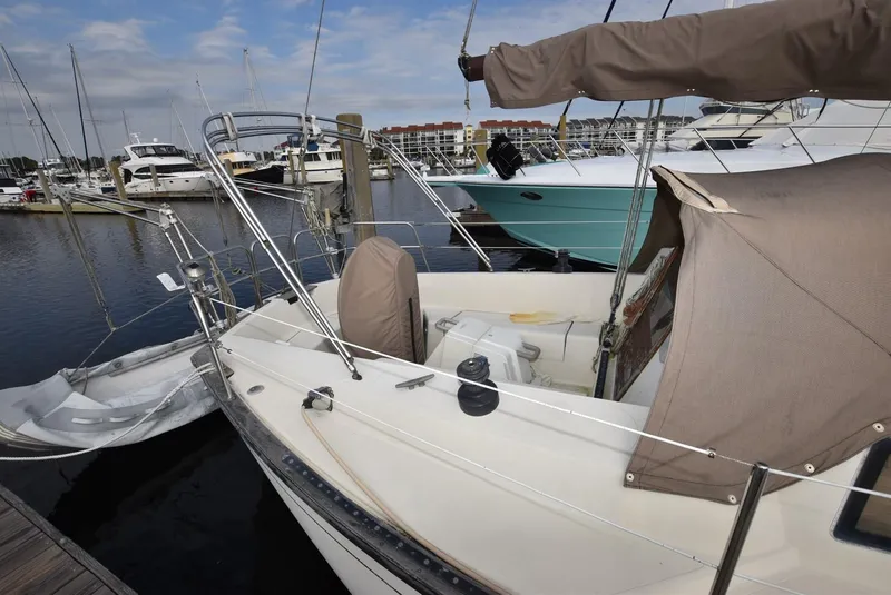 Slide: The Image of 1983 S2 Sloop sailboat docked at marina with covered cockpit and nearby yachts. - 3