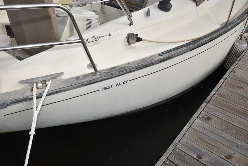 Slide: The Image of 1983 S2 Sloop sailboat docked, featuring sleek white hull and deck details. - 9