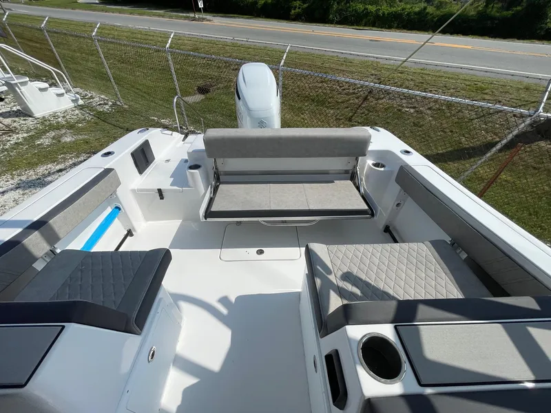 Slide: The Image of 2025 Sea Pro 240 Dual Console boat interior with seating and storage, parked near a road. - 24