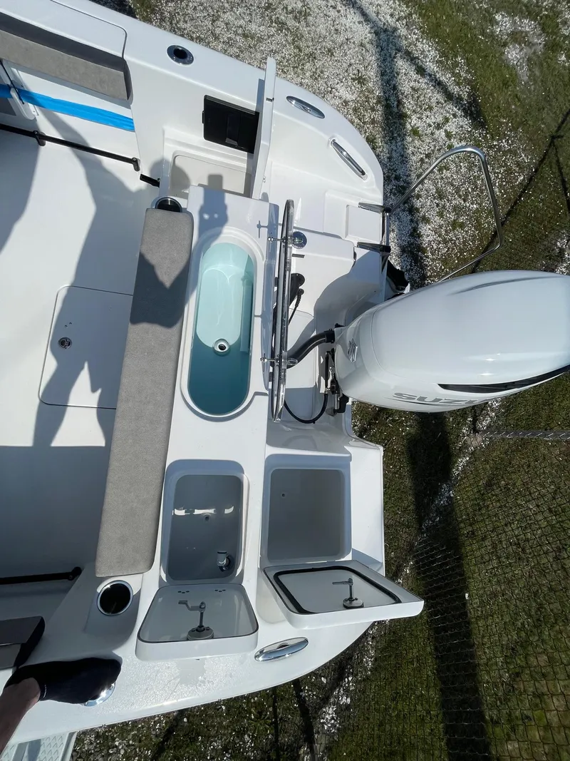 Slide: The Image of 2025 Sea Pro 240 Dual Console boat deck with storage compartments and outboard motor. - 25