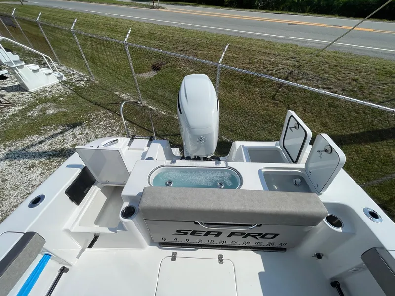 Slide: The Image of 2025 Sea Pro 240 Dual Console boat with seating and storage, parked near a road. - 27