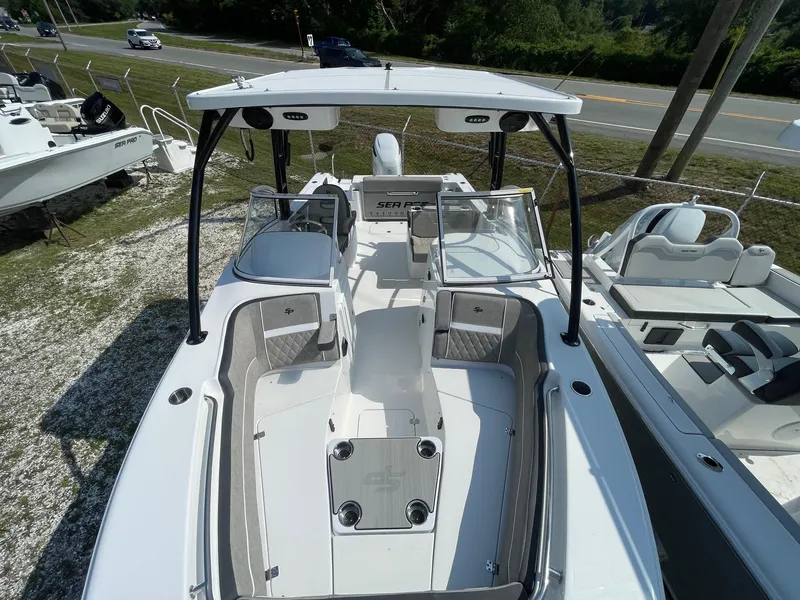 Slide: The Image of 2025 Sea Pro 240 Dual Console boat, sleek design, spacious seating, parked outdoors. - 9