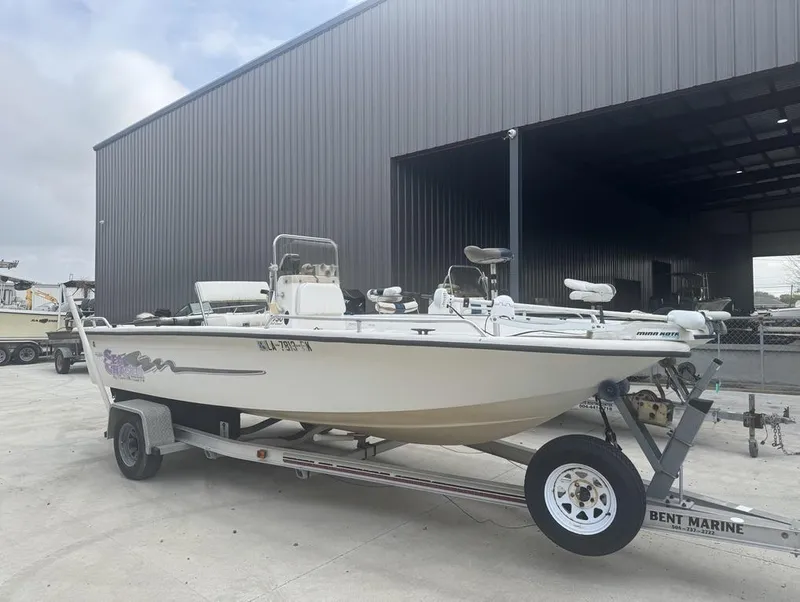 Slide: The Image of 2018 Mako Pro Skiff 19 CC Top Drive boat on trailer near large warehouse. - 4