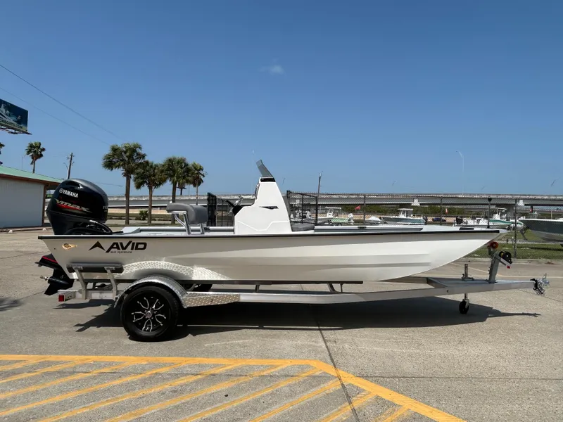 Slide: The Image of 2025 Avid 20 ROGUE CC boat on trailer, parked outdoors under clear blue sky. - 5