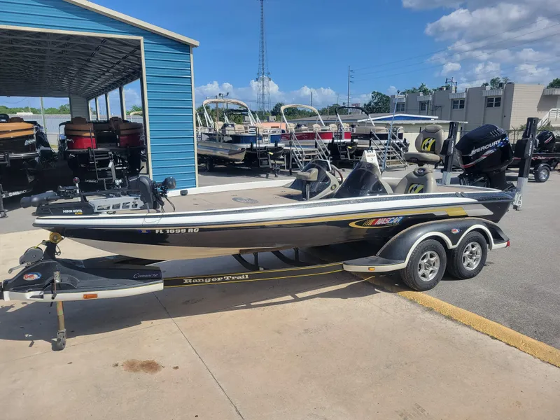 Slide: The Image of 2003 Ranger 521VX NASCAR boat on trailer, parked at a marina under a clear blue sky. - 1
