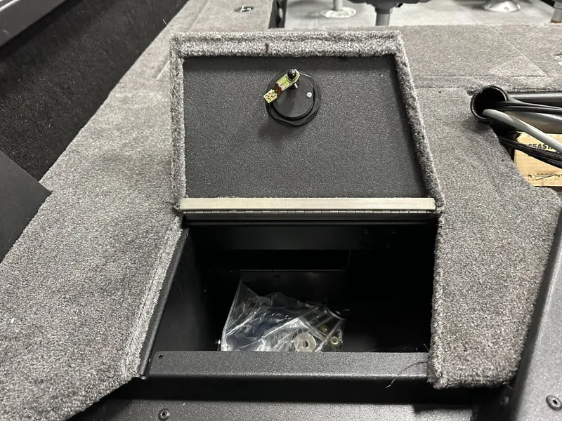 Slide: The Image of 2025 Alumacraft Competitor 185X Sport boat storage compartment with carpeted interior. - 16