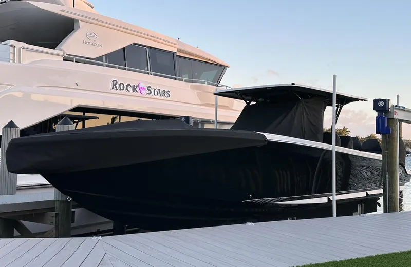 Slide: The Image of 2023 Nor-Tech 390 Sport Center Console boat docked beside a luxury yacht. - 12