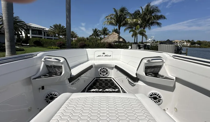Slide: The Image of 2023 Nor-Tech 390 Sport Center Console boat interior with seating and speakers, surrounded by palm trees. - 5