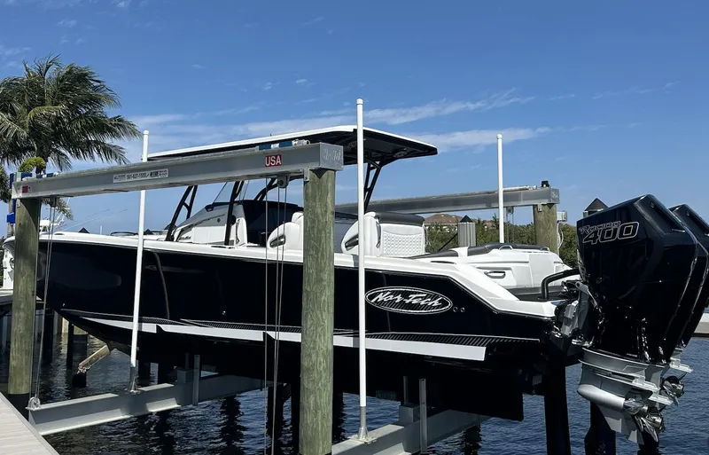 Slide: The Image of 2023 Nor-Tech 390 Sport Center Console boat on lift, docked by palm trees. - 9