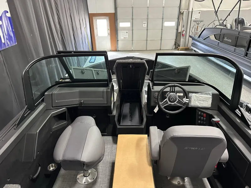 Slide: The Image of 2025 Alumacraft Competitor 185X Sport interior with dual seats and steering console in a garage setting. - 13