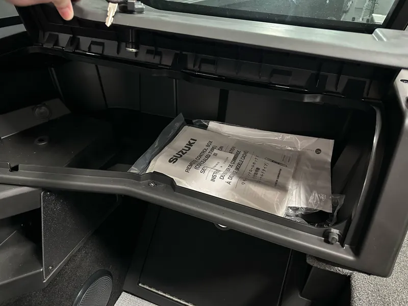 Slide: The Image of Open glove compartment of 2025 Alumacraft Competitor 185X Sport with Suzuki manual inside. - 20