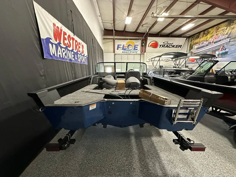 Slide: The Image of 2025 Alumacraft Competitor 185X Sport boat displayed in a showroom with marine banners. - 4