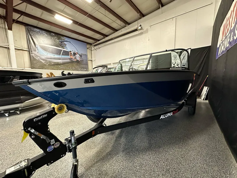 Slide: The Image of 2025 Alumacraft Competitor 185X Sport boat on trailer in showroom. - 6