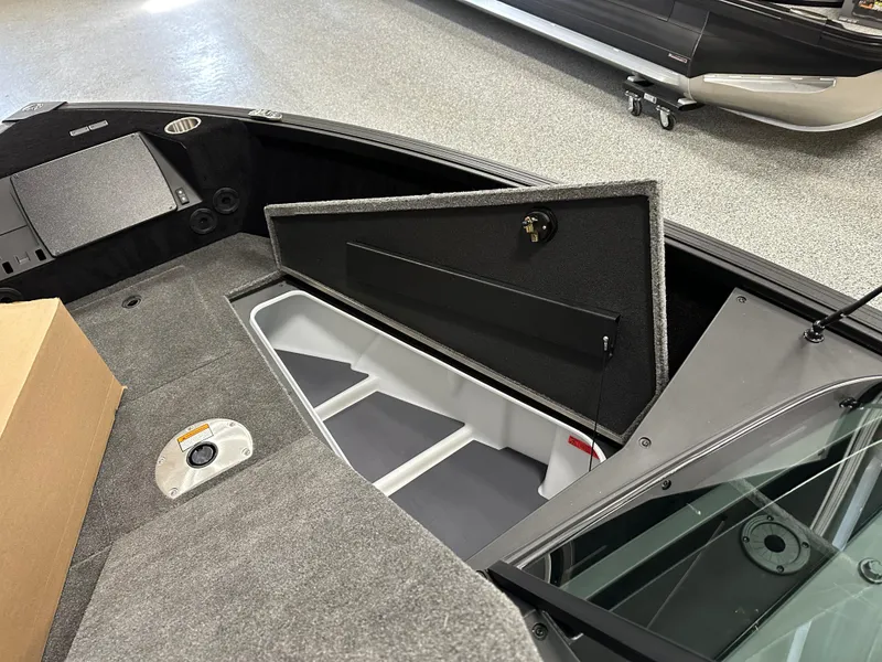 Slide: The Image of 2025 Alumacraft Competitor 185X Sport boat interior storage compartment open. - 11