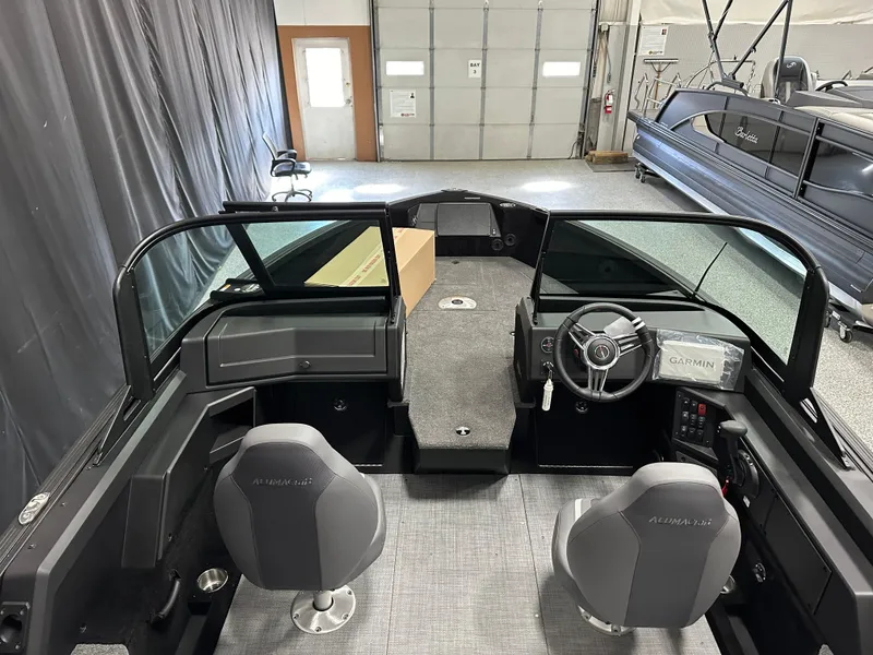 Slide: The Image of 2025 Alumacraft Competitor 185X Sport interior with steering wheel and seating in a showroom. - 8